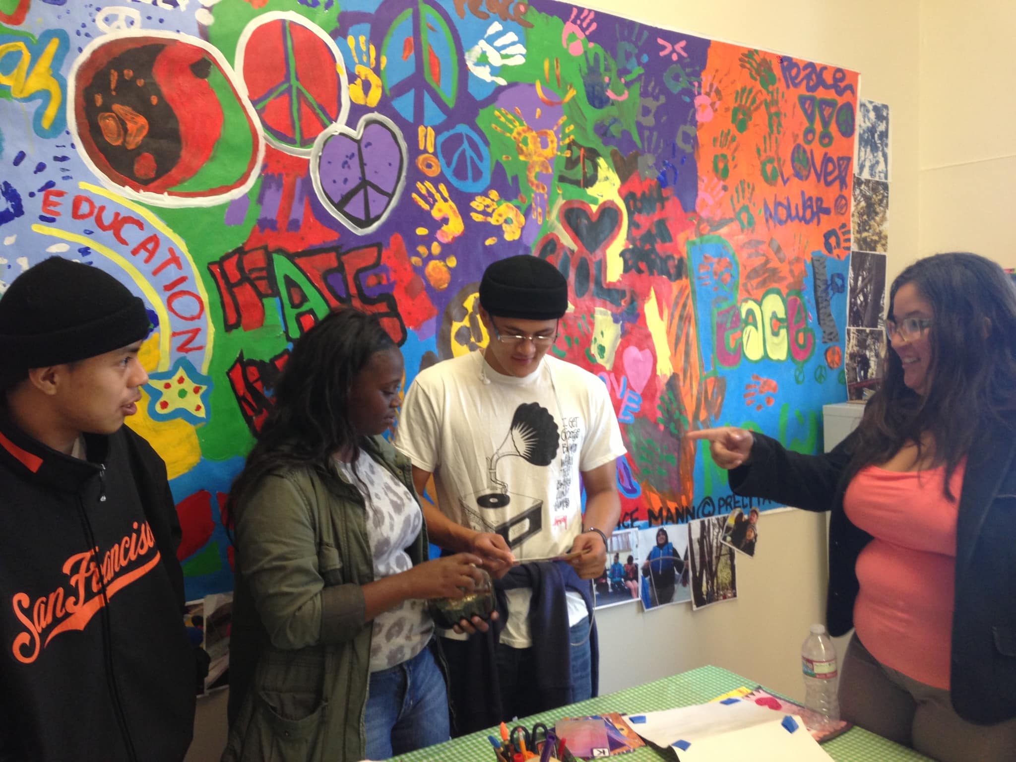 students talk to each other in front of a colorful mural