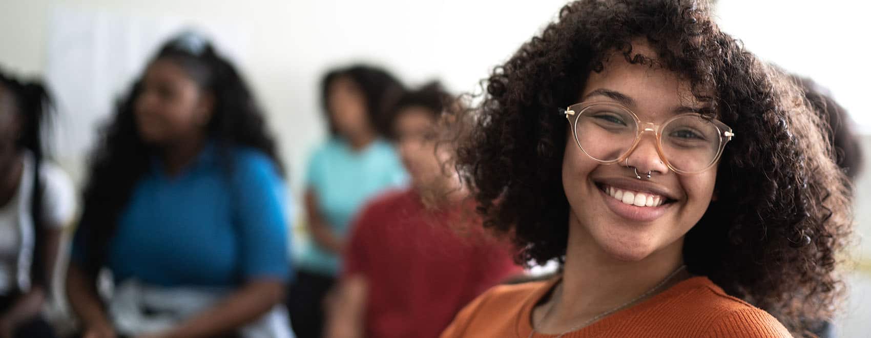 Portrait of a female student of color in a classroom smiling