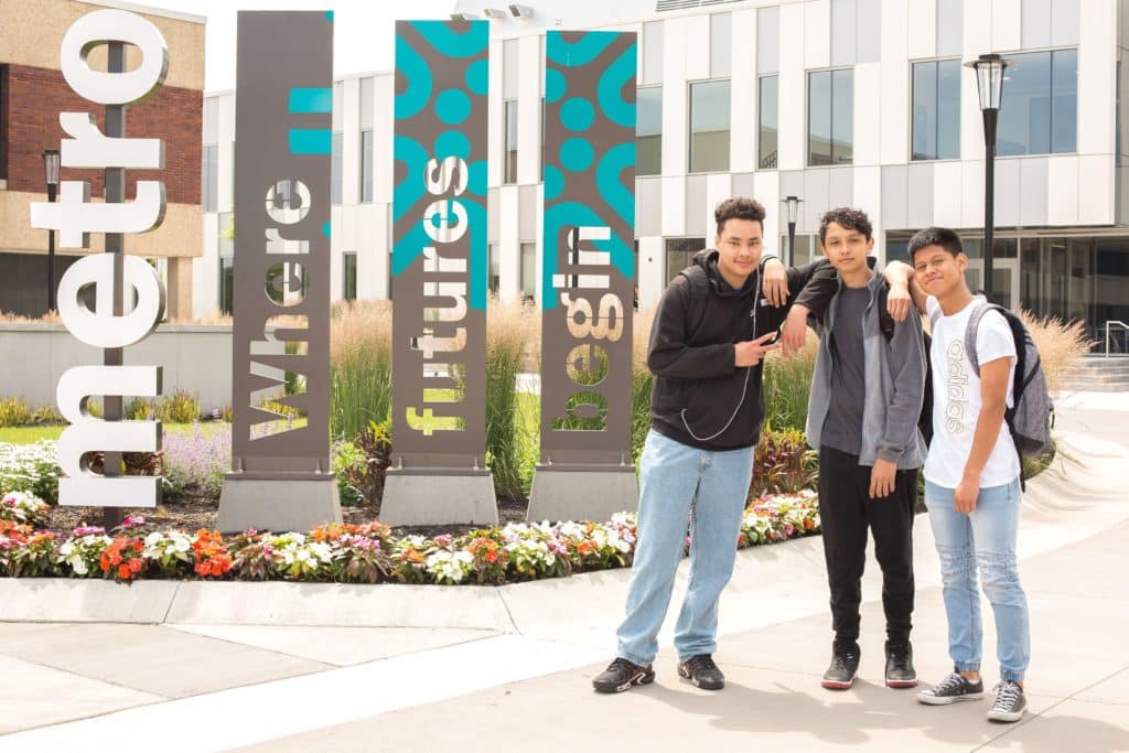 Three students stand outside one of Tri-C's campus building