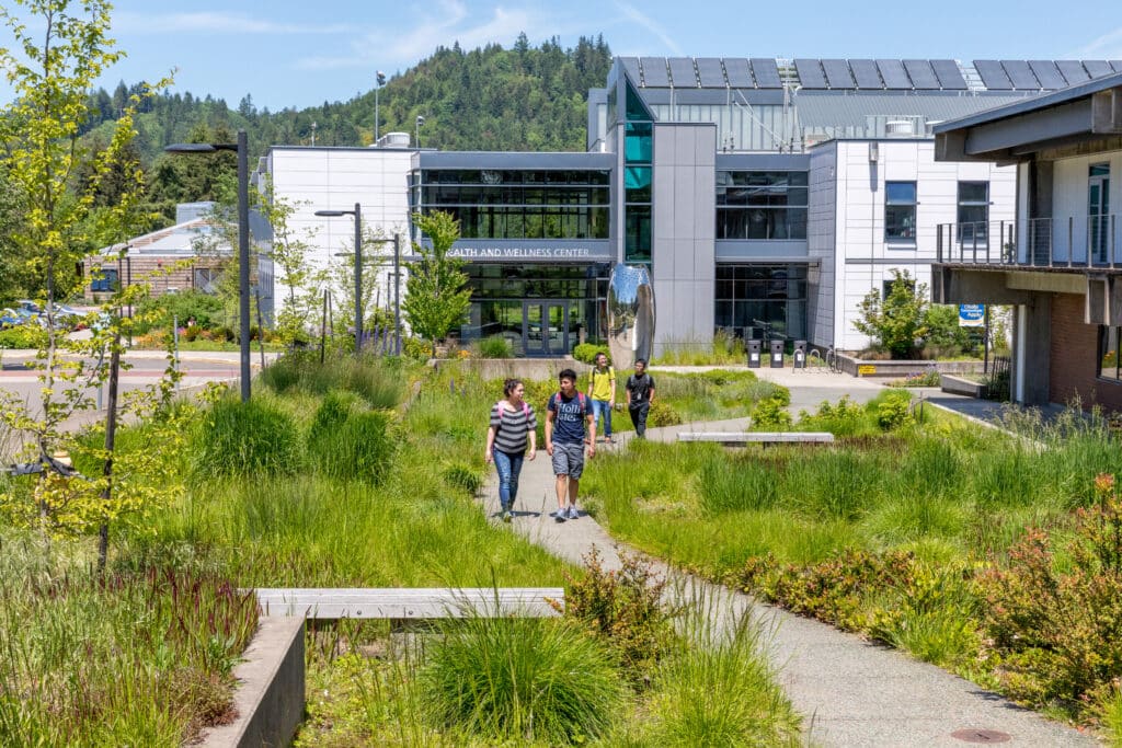 Students walk along a curving path in front of the Health and Wellness Center at Lane Community College