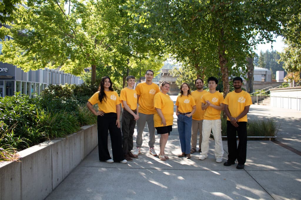 Members of the Lane Community College Student Government Association stand in a row, wearing matching orange "SGA" t-shirts.